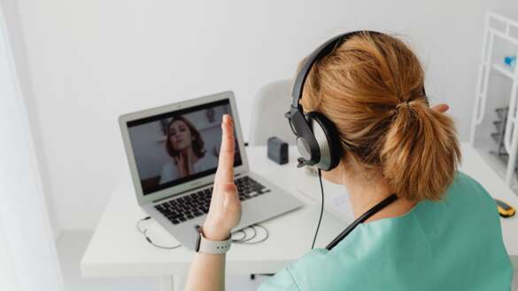 Assistierte Telemedizin: Patientin sitzt vor dem Laptop und wird von einer zugeschalteten Ärztin beraten