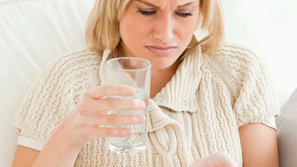 Frau mit Wasserglas und Tablette