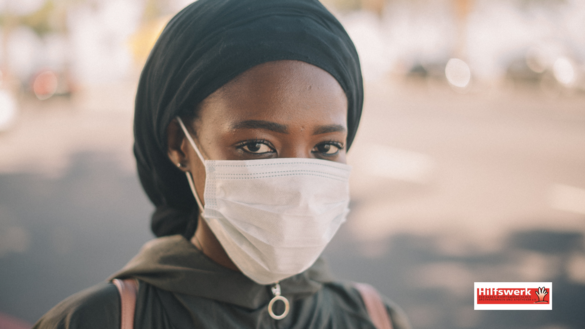 Frau aus Kongo mit Mundschutz-Maske schaut in die Kamera